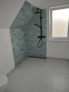 Murerarbejde i badeværelse med blå mosaikfliser og præcis fugning.